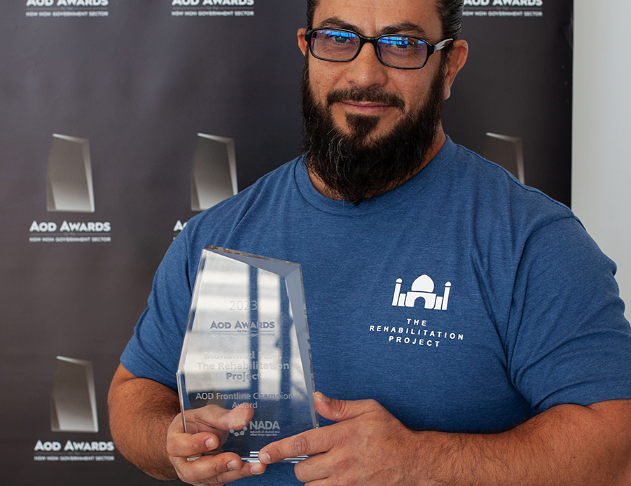 Bearded man with glasses holding acrylic award